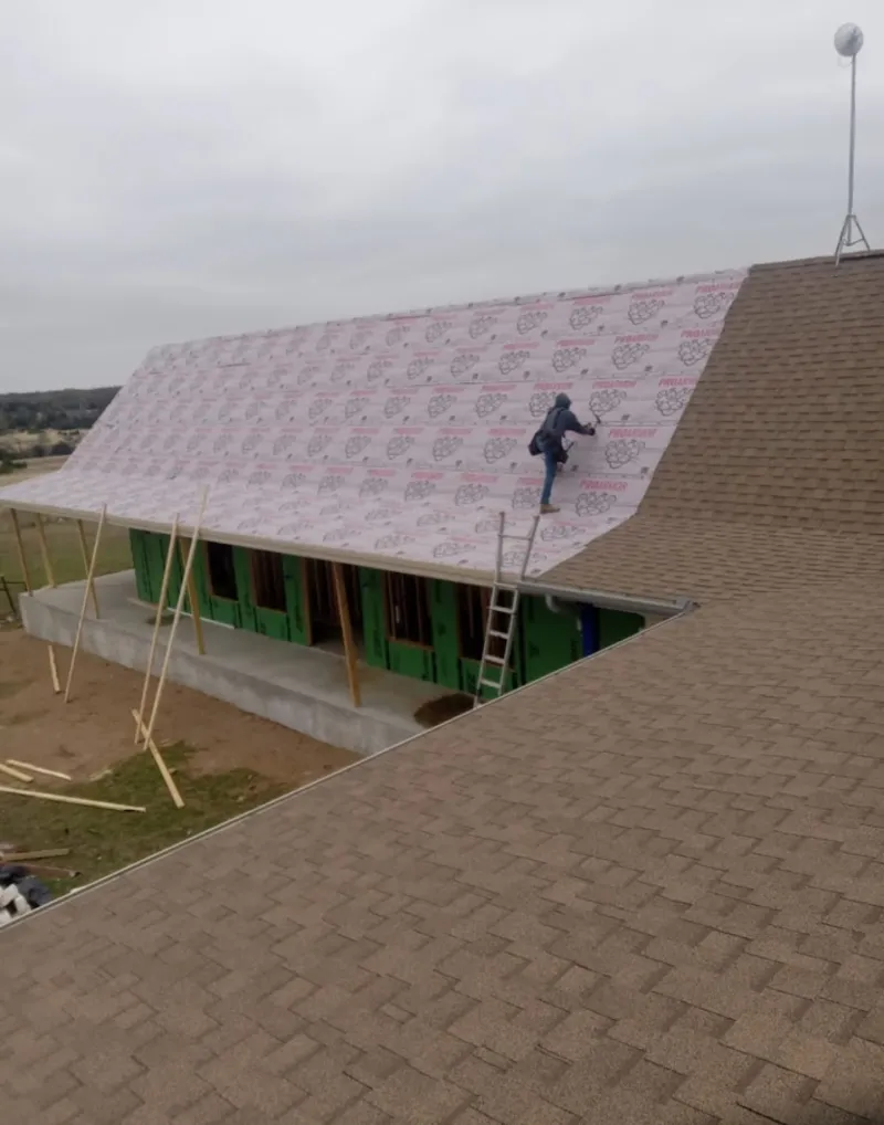 Worker preparing underlayment for a metal roof installation in Pocahontas